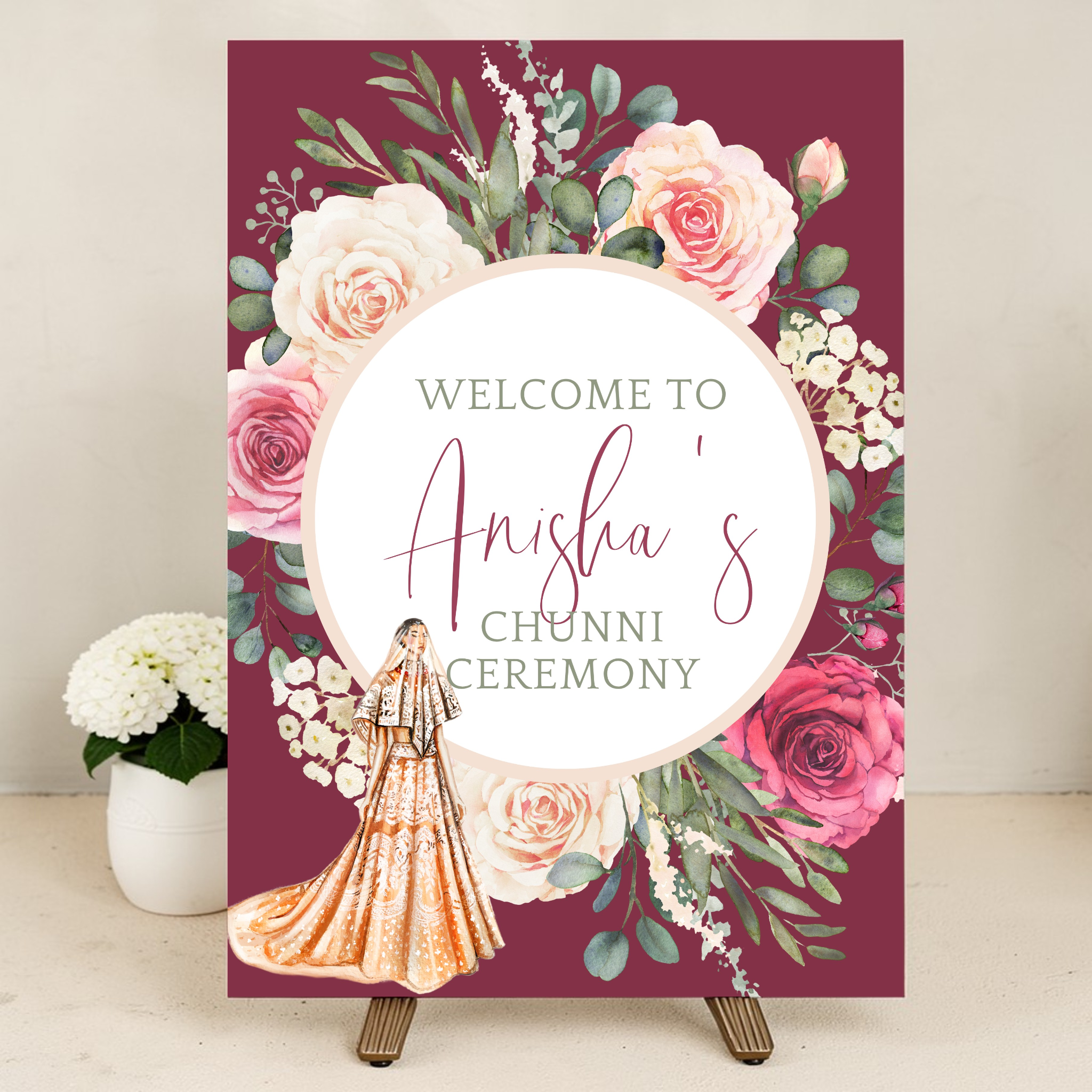 Personalised Indian wedding welcome sign on easel at Chunni ceremony entrance decorated with pink and white floral arrangements