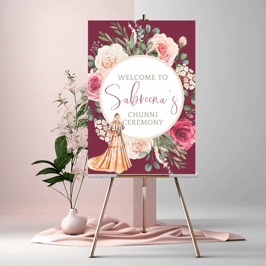 Personalised Chunni ceremony welcome sign with illustrated Indian bride in lehenga, watercolour roses and burgundy background, displayed on a wooden easel