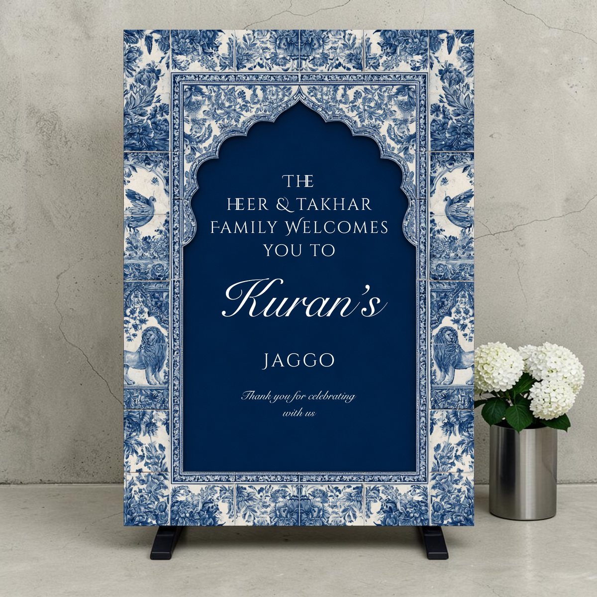 Personalised Jaggo night welcome sign printed on 3mm foamex. Navy blue Mughal arch on intricate blue and white floral tile border with lion and bird motifs. Custom two-family names, bride or groom name in script and Thank You for Celebrating With Us. A1 or A2. By Krafty Kaur.
