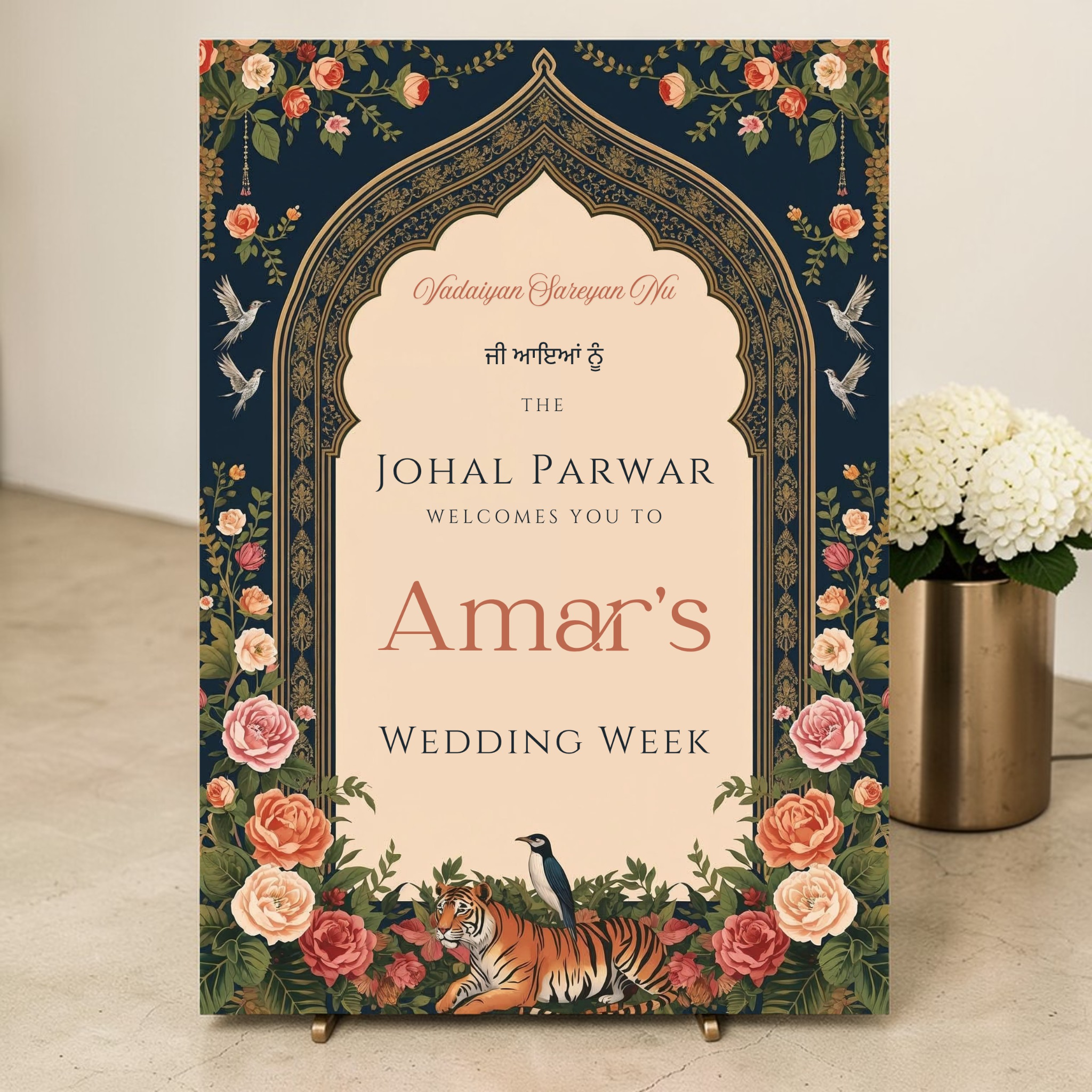 Personalised Indian wedding week welcome sign printed on 3mm foamex, featuring Mughal arch in navy and gold, botanical florals, illustrated tiger and peacock, displayed on a brass easel