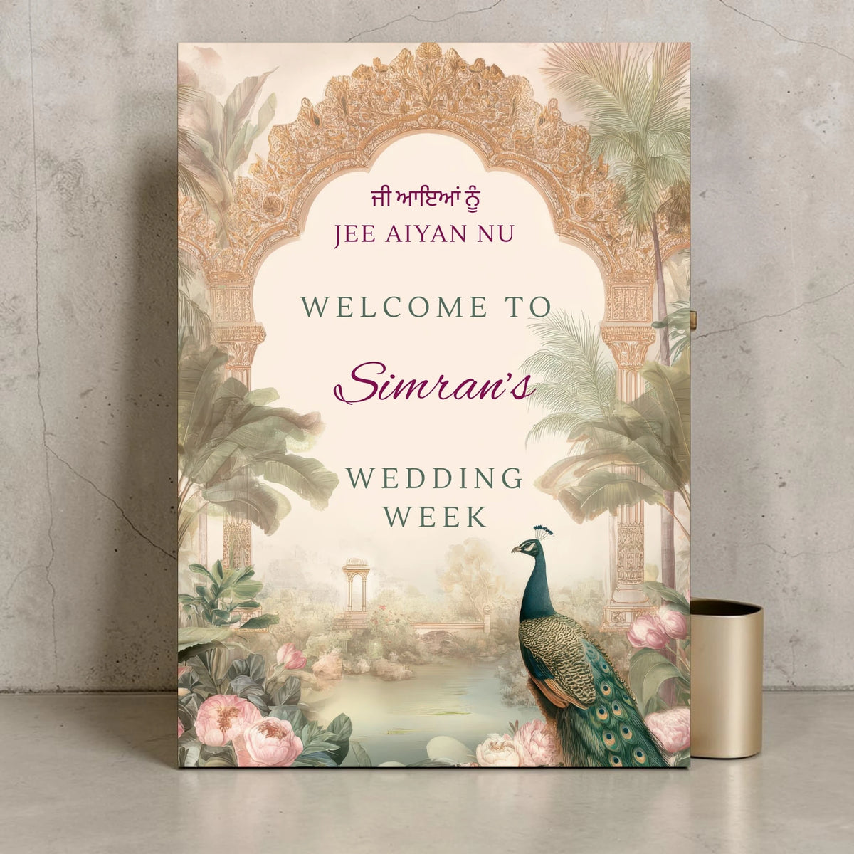 Personalised Punjabi wedding week welcome sign printed on 3mm foamex. Blush and sage Mughal arch with ornate gold carving, peacock, tropical palms, pink peonies and misty Indian garden illustration. Jee Aiyan Nu in Gurmukhi, custom name in plum script. A1 or A2. By Krafty Kaur.