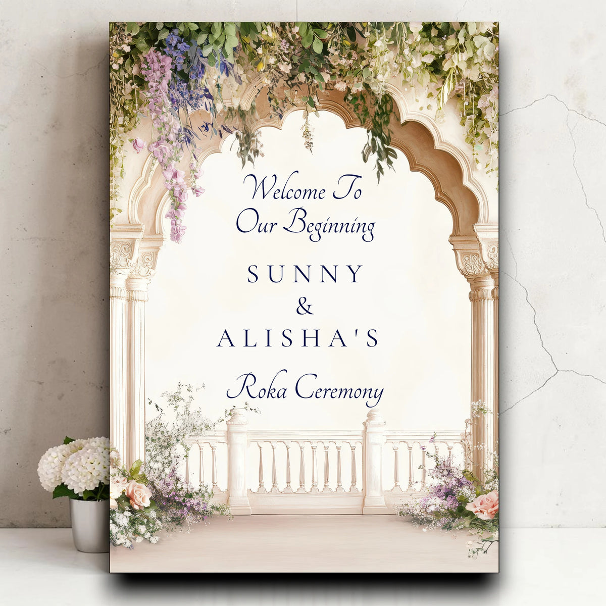 Personalised Roka ceremony welcome sign printed on 3mm foamex displayed on gold easel featuring sandstone Mughal arch draped in wisteria wild roses and trailing greenery with navy couple names on cream background