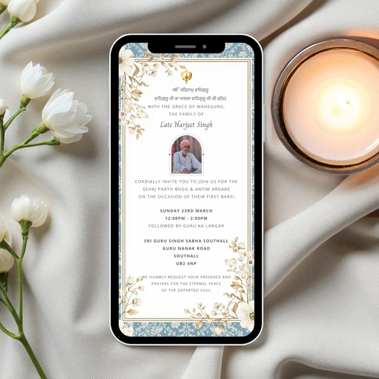 Phone displaying a digital sikh death anniversary barsi invitation with flowers and a candle on a soft fabric background