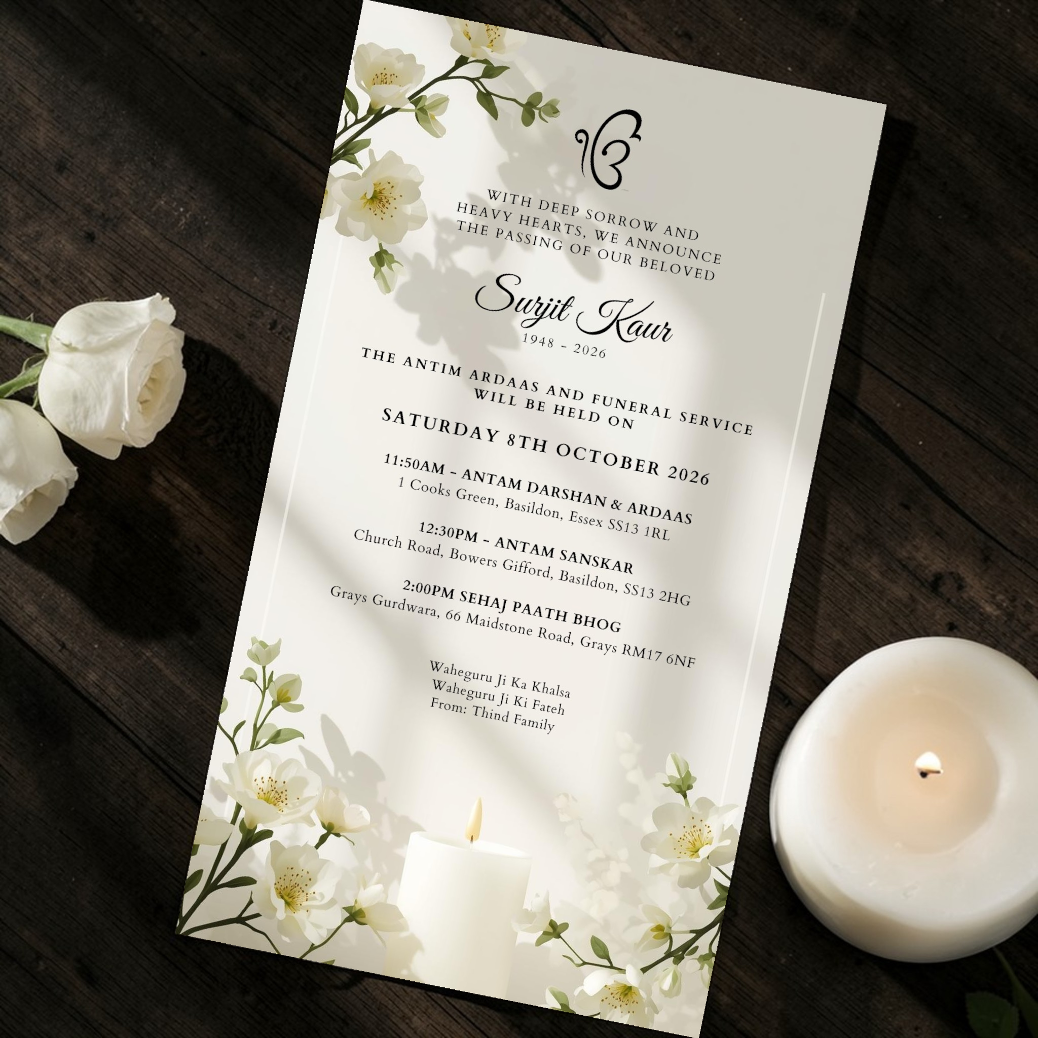 Sikh Funeral service invitation card with floral design on a wooden surface with candles and flowers.